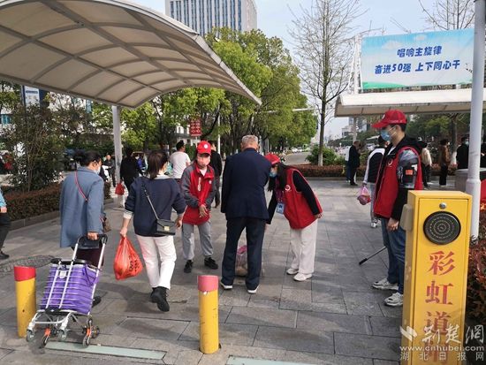 志愿服務(wù)隊(duì)在人民醫(yī)院路口開展文明交通體驗(yàn)活動，并幫助老人提重物.jpg.jpg